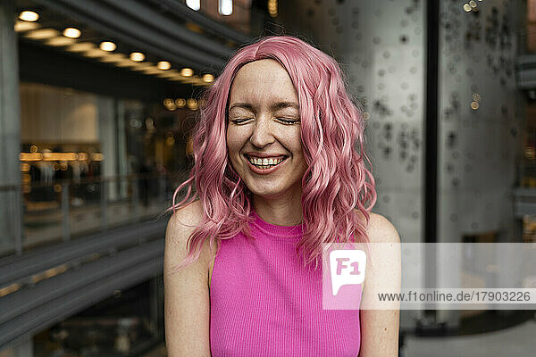 Fröhliche junge Frau mit rosa gefärbten Haaren