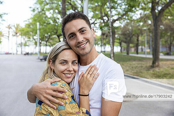 Smiling young couple hugging each other at park