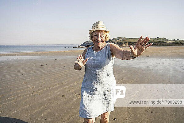 Fröhliche Seniorin tanzt und hat im Urlaub Spaß am Strand