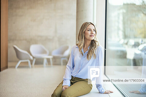 Smiling businesswoman looking through window in office