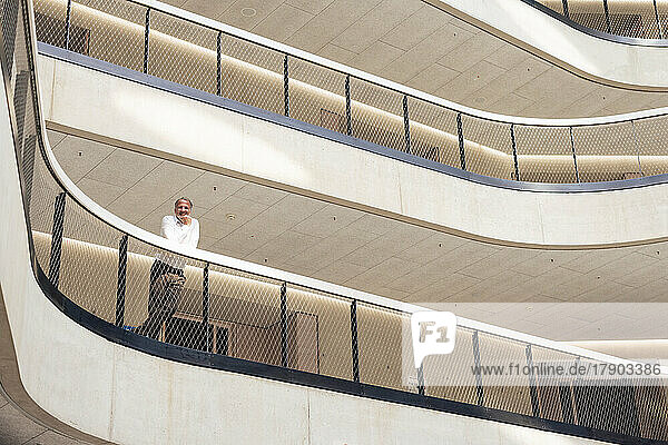 Senior businessman leaning on railing in corridor