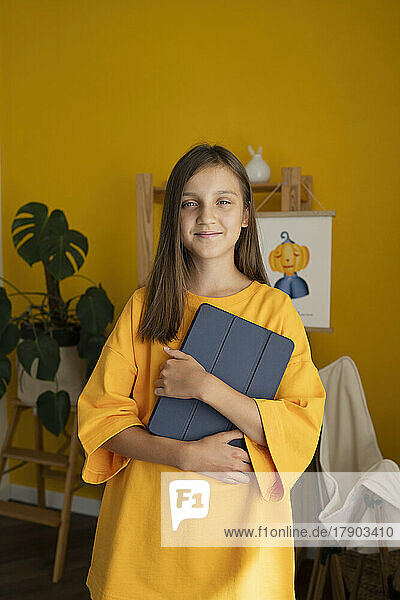 Smiling girl with tablet PC standing at home