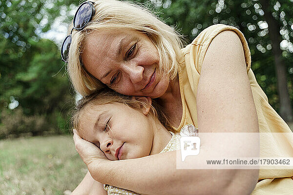 Lächelnde Großmutter umarmt Enkelin im Park