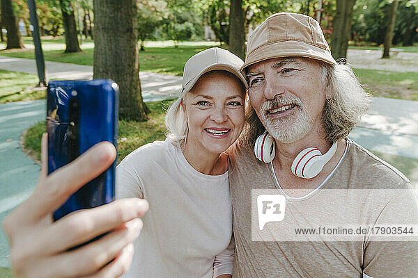 Happy couple taking selfie through smart phone at park