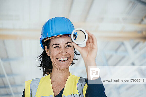 Happy engineer wearing reflective clothing holding ring shape object in factory