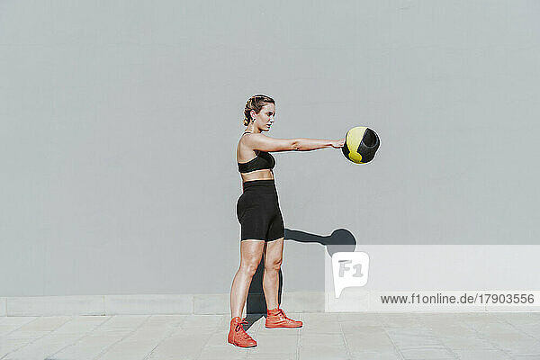 Young woman exercising with medicine ball on sunny day