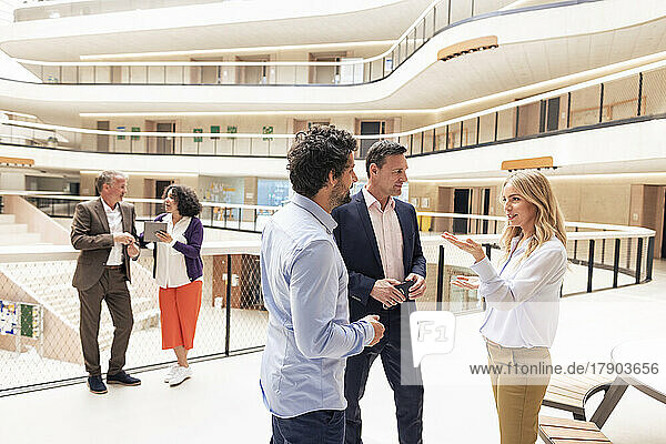 Businesswoman discussing strategy with colleagues in corridor