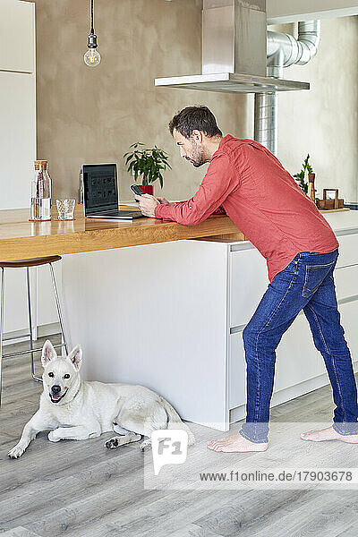 Man using smart phone leaning on table at home