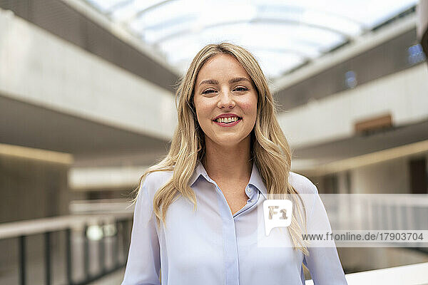 Smiling businesswoman with blond hair in corridor