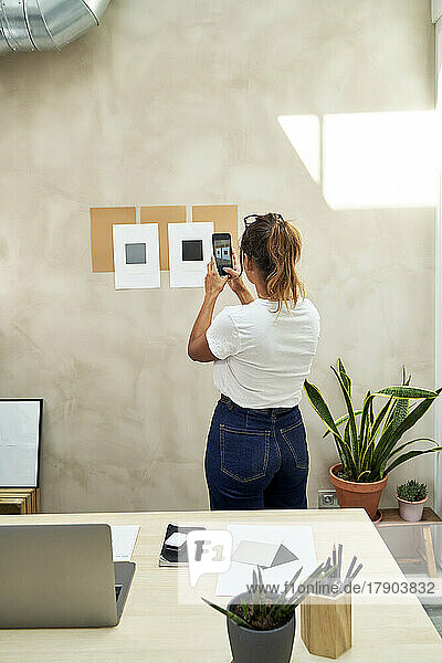 Freelancer taking picture of business strategy on wall at home office