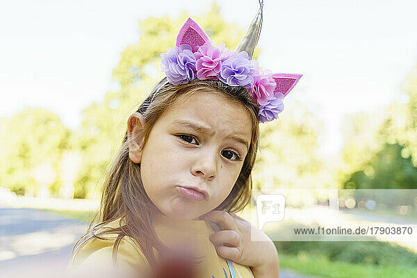 Girl wearing unicorn headband taking selfie at park