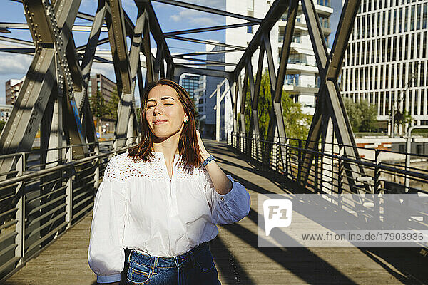 Smiling woman enjoying sunlight on bridge