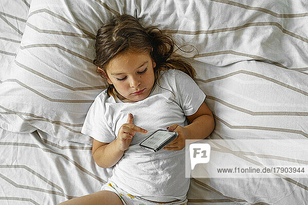 Girl using smart phone on bed at home