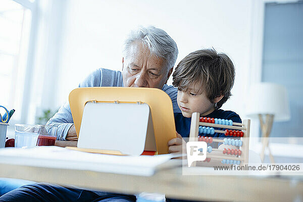 Senior man and boy using tablet PC at home