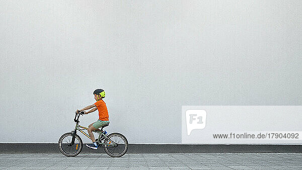 Junge fährt BMX-Fahrrad an weißer Wand