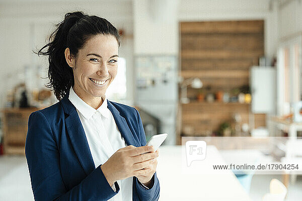 Happy businesswoman holding mobile phone