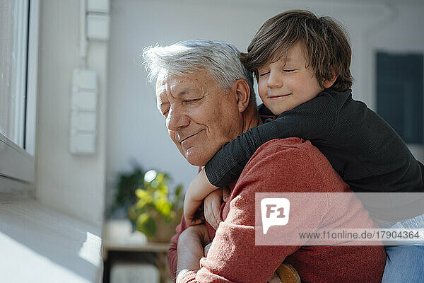 Grandfather and grandson with eyes closed at home