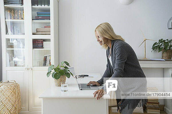 Mature freelancer using laptop on desk at home office