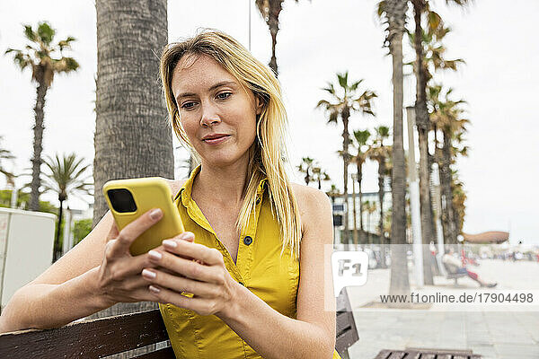 Woman using smart phone sitting on bench