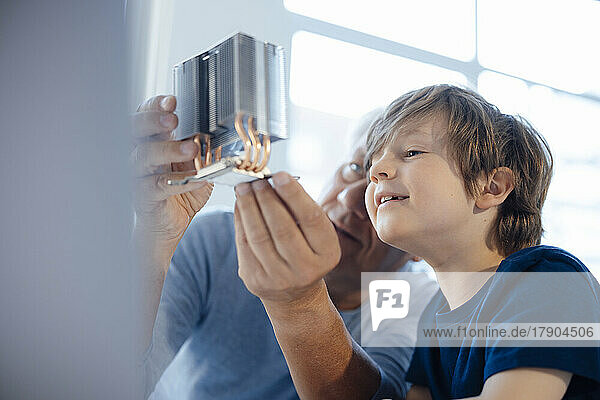Grandfather examining model object by grandson at home