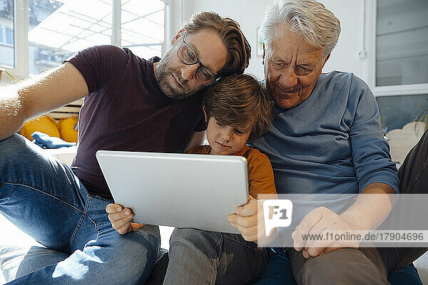 Mehrgenerationenfamilie schaut sich zu Hause einen Film auf einem Tablet-PC an