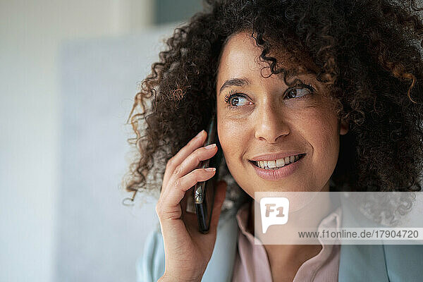 Contemplative businesswoman talking on smart phone at office