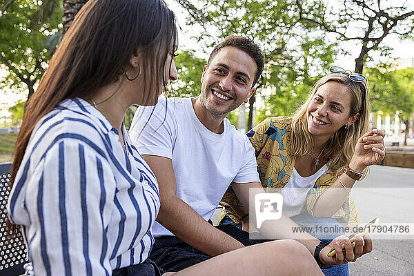 Glückliche Freunde  die miteinander reden und im Park sitzen