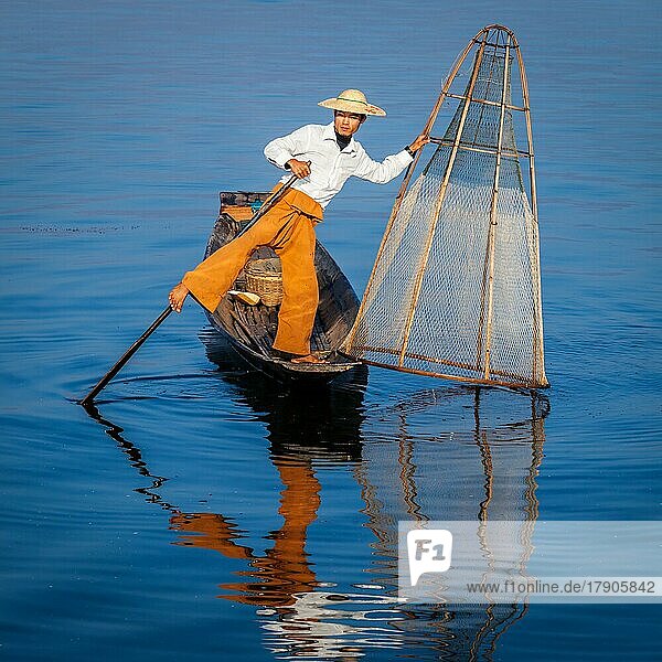 Myanmar travel attraction landmark  Traditional Burmese fisherman with fishing net at Inle lake in Myanmar famous for their distinctive one legged rowing style