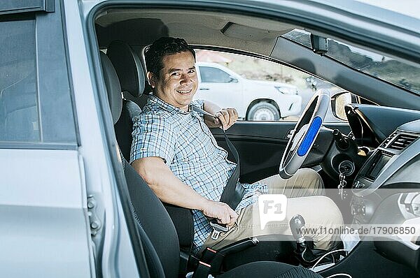 Lächelnder männlicher Fahrer beim Anlegen des Sicherheitsgurtes. Konzept eines Fahrers in seinem Auto  der seinen Sicherheitsgurt anlegt. Lächelnde Person beim Anlegen des Sicherheitsgurtes  Glücklicher Fahrer beim Anlegen des Sicherheitsgurtes