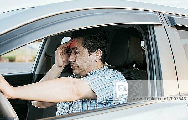 A driver with a headache in traffic  fatigued driver stuck in traffic  concept of a fatigued man in his car  stressed out. A suffering person with a headache in traffic