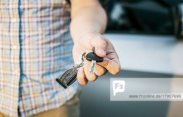 Hände des Fahrers zeigen die Autoschlüssel  Nahaufnahme von männlichen Fahrer Hände zeigen die Schlüssel  Fahrzeugvermietung Konzept. Nahaufnahme von Menschen halten Autoschlüssel
