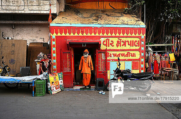 Hindu-Pundit in heiligem Orange an einem winzigen Hindu-Tempel in der Nähe des Gomati Ghat  Dwarka  Gujarat  Indien  Asien