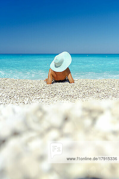 Frau mit Strohhut betrachtet das Meer am Strand im Sommer  Kefalonia  Ionische Inseln  Griechische Inseln  Griechenland  Europa