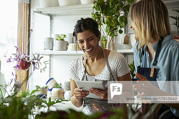 Fröhliche Blumenladenbesitzerin mit digitalem Tablet