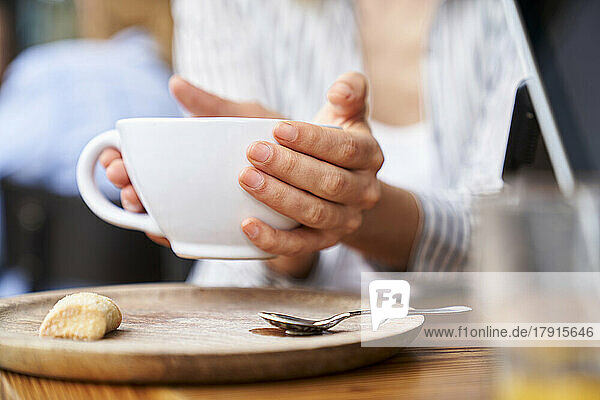 Nahaufnahme der Hände einer Frau  die eine Tasse Kaffee halten