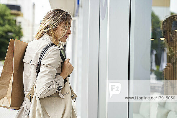 Seitenansicht einer Frau  die beim Schaufensterbummel Taschen trägt