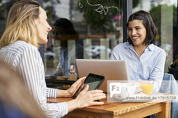 Mid-shot of two smiling female co-workers enjoying their work in outdoors office
