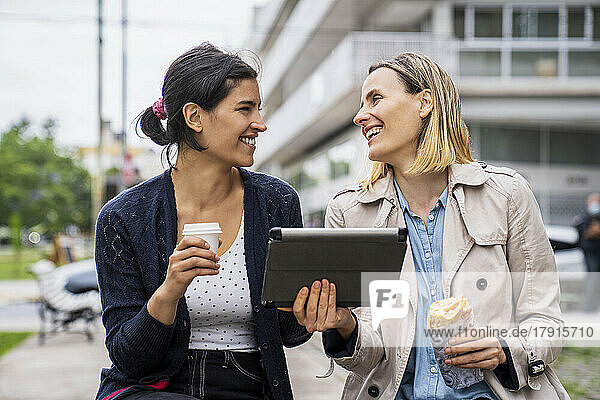 Front view shot of two female digital nomads working outdoors and having a good time