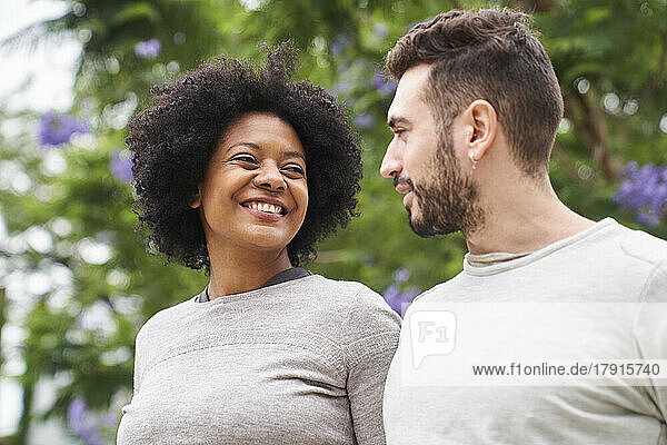 Porträt einer afroamerikanischen Frau und eines kaukasischen Mannes  die sich gegenseitig anlächeln und eine gute Zeit im Freien haben