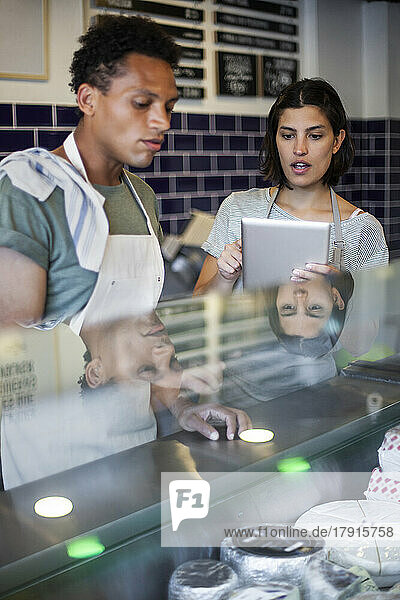 Mitarbeiter eines Lebensmittelladens diskutieren über ein digitales Tablet