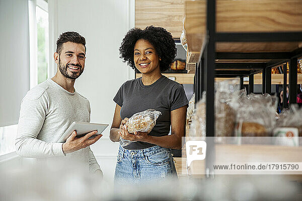 Male and female entrepreneur looking at the camera while standing in pastry store