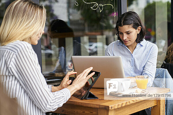 Mittlere Einstellung von zwei weiblichen Mitarbeitern  die sich auf ihre Arbeit im Büro im Freien konzentrieren