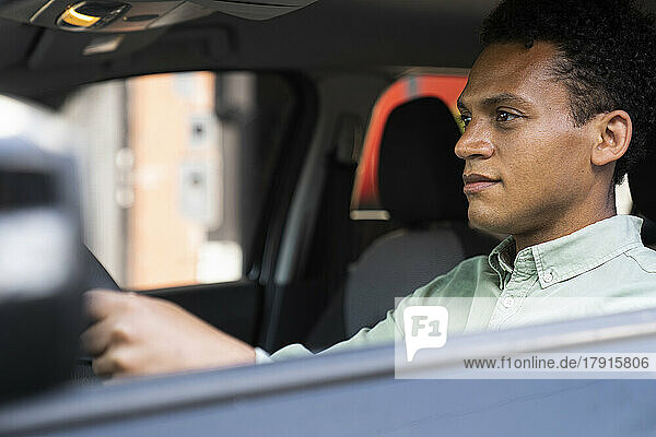 Seitenansicht eines gut aussehenden afroamerikanischen Mannes in seinem Auto auf dem Weg zur Arbeit
