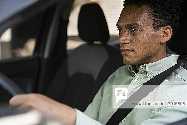 Porträt aus der Mitte des Fahrzeugs eines afroamerikanischen Geschäftsmanns  der mit seinem Auto zur Arbeit fährt