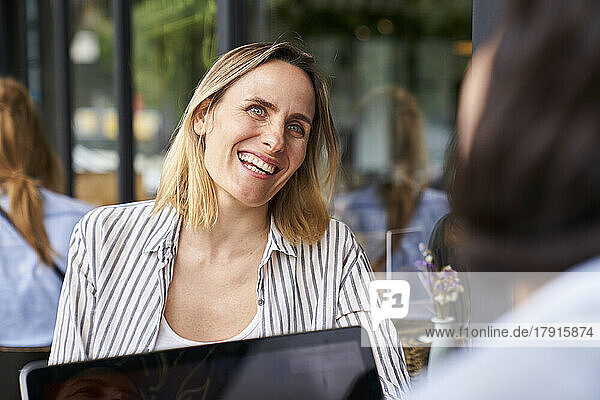 Front view shot of amused female entrepreneur having a good time while working in outdoors office with partner