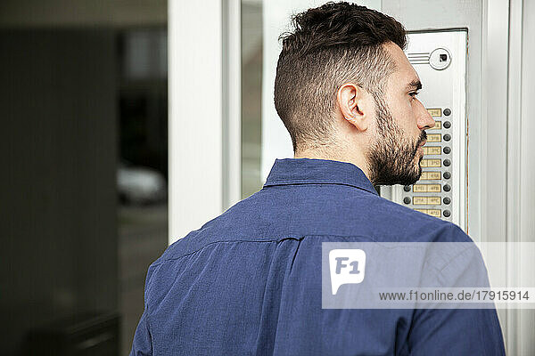 Delivery man standing in doorway while waiting to be attended