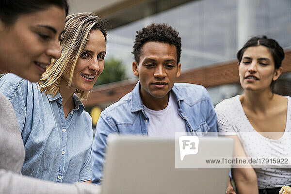 Verschiedene Gruppen von freiberuflichen Auftragnehmern  die im Freien auf einen Laptop-Bildschirm schauen