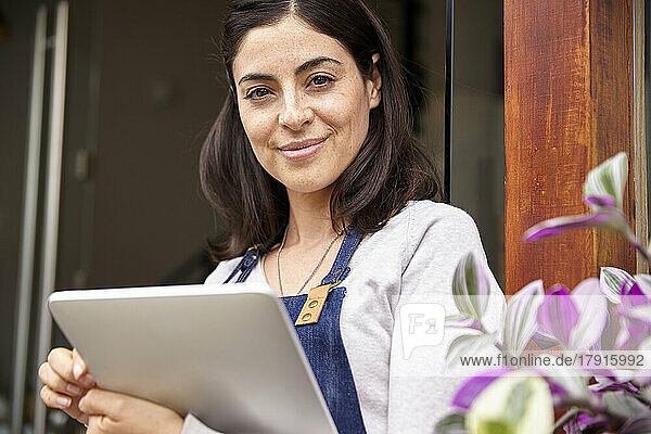 Female entrepreneur looking at the camera while holding digital tablet