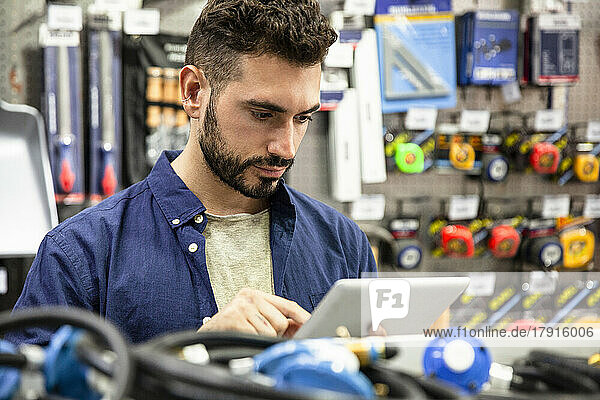 Männlicher Inhaber eines Eisenwarengeschäfts bei der Inventur auf einem digitalen Tablet
