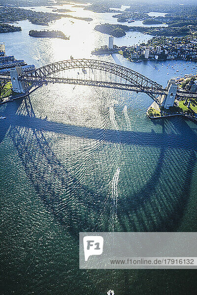 Die Sydney Harbour Bridge  der Schatten des Bogens auf dem Wasser und eine Luftaufnahme der Landschaft.